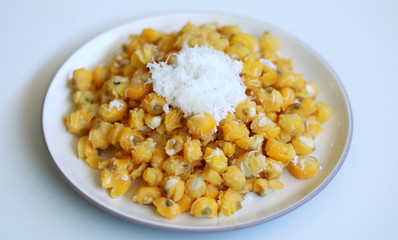 Grontol jagung on white background.  Grontol jagung is traditional snacks in Indonesia. Boiled shelled corn sprinkled with grated coconut.