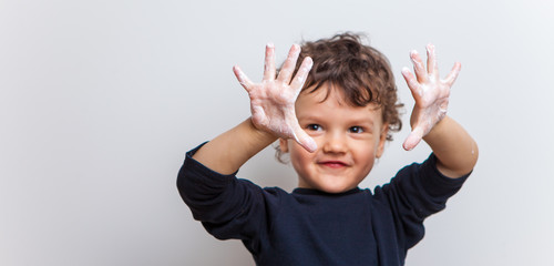 funny and joyful baby shows his soapy palms