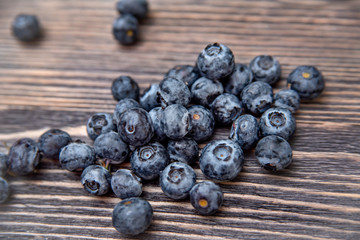 randomly scattered blueberries on a wooden background in the center of the frame close up