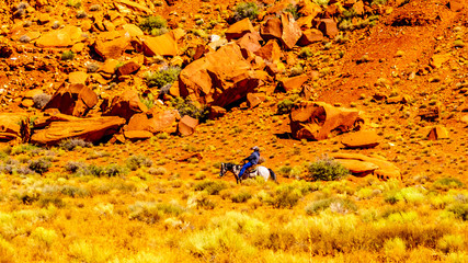 A Navajo riding a horse through Monument Valley, a Navajo Tribal Park on the border of Utah and Arizona, United States