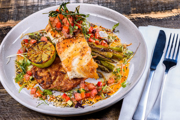 A serving of Grilled Snapper fish with Asparagus, Roasted Potato, grilled lemon and salsa
