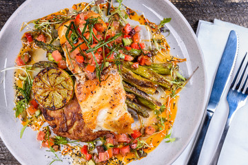 A serving of Grilled Snapper fish with Asparagus, Roasted Potato, grilled lemon and salsa