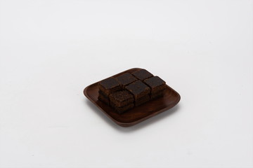 Brown sugar is placed in wooden plates, isolated on a white background. Red ginger sugar is a blood tonic food. It is made by pressing and boiling sugarcane