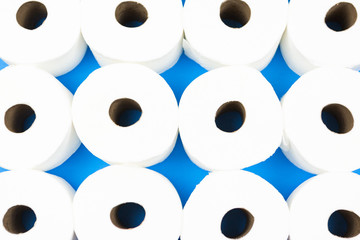 Background pattern mosaic of toilet paper rolls lay flat on the bright blue background. Coronavirus pandemic panic shopping concept.