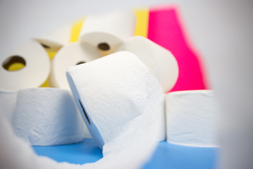 Pile of toilet paper rolls and one roll in front with camera wrapping effect on yellow blue pink color background hoarding amid panic buying for corona virus outbreak shortage.