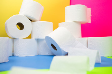 Stockpile of toilet paper rolls on colorful background. Many rolls at home in fear of corona virus outbreak closing shopping stores.