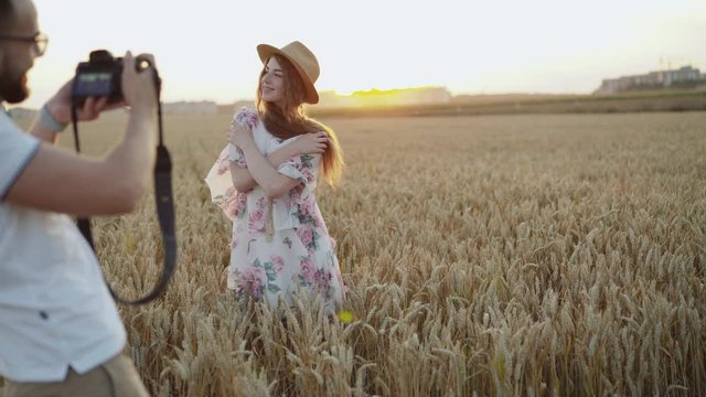 Amazing lady with natural beauty poses at photographer in field on sunset