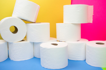 Stockpile of toilet paper rolls on colorful background. Many rolls at home in fear of corona virus outbreak closing shopping stores.