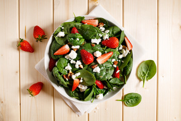 Healthy vegetable salad of fresh spinach, strawberries, feta cheese and almond on plate.