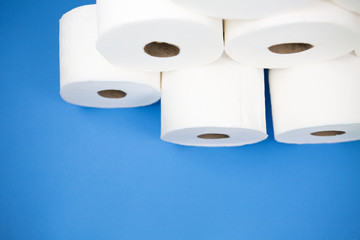 Pile toilet paper rolls shown on light blue background. Fear of corona virus outbreak closing shopping stores.