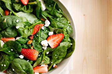 Healthy vegetable salad of fresh spinach, strawberries, feta cheese and almond on plate.