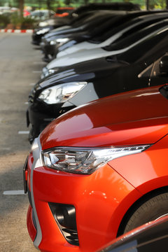 Closeup of front side of red car with other cars parking in parking area. Vertical view. © Amphon
