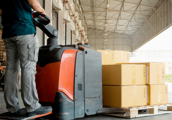 Worker courier driving electric forklift pallet jack loading the goods.  packaging boxes, warehouse delivery service customers shipment  transport.
