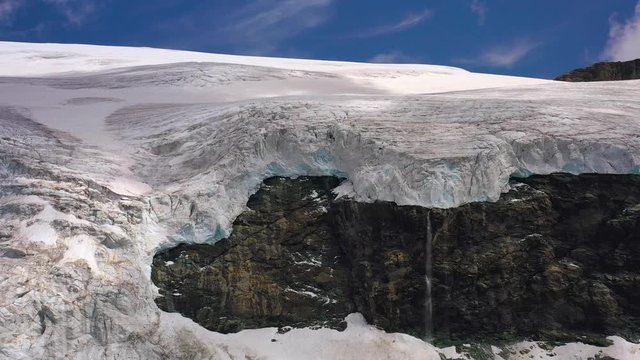 Aerial, reverse, drone shot away from a waterfall and the Monte Rosa glacier, in Valle'd Aosta valley, Italy