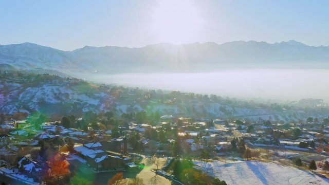 Aerial move over snow-covered high-end neighborhood at sunrise in SLC Utah