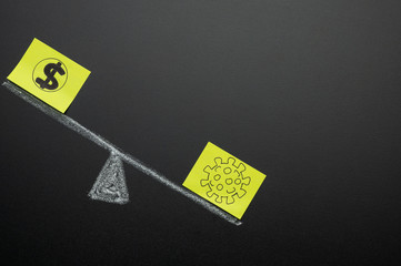 Coronavirus and dollar on the scales drawn on a blackboard. The concept of the economic crisis for the coronavirus and the massive epidemic or pandemic