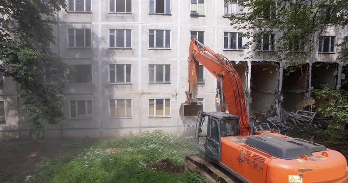 An excavator destroys the external wall of a residental building with its bucket