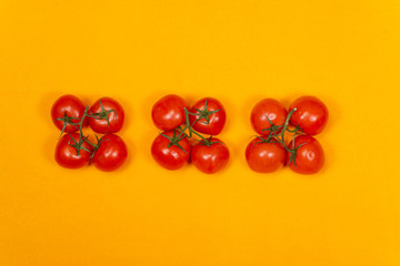 Red tomatoes on a branch on a yellow background, top view