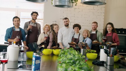 Portrait of multi-ethnic group of people standingin cooking class together smiling laughing looking at camera. Free time activity and cooking meals concept.