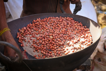 peanut roasted in sand ,Roasting Peanut in Kadai (Indian Utensil) with Sand for Selling in an  road side,Peanut vendor roasting peanuts during smog in a cold day at Beawar.