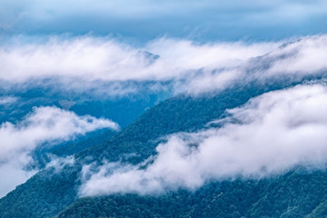 High mountain with green slopes hidden in clouds and fog.