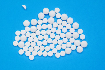 Lots of white pills on a blue background. Search for a cure for COVID-19, medicine concept. Horizontal orientation. Selective focus. View from above.