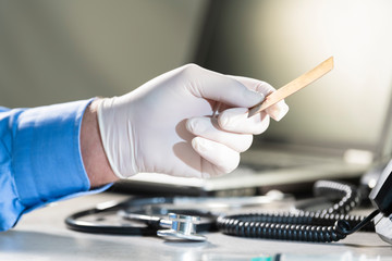 Male hand in a glove holding a credit card over a stethoscope