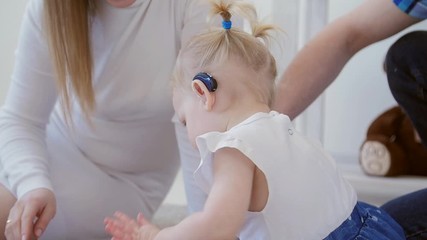 Concept of hearing impairment and their treatment. Cute little girl with a hearing aid