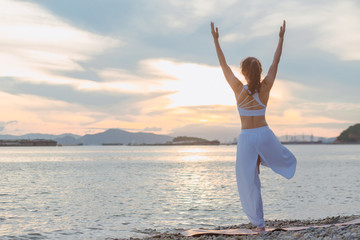 Young woman is practicing yoga at mountain lake