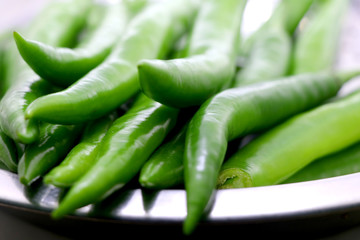 bunch of fresh green chili peppers on a white background