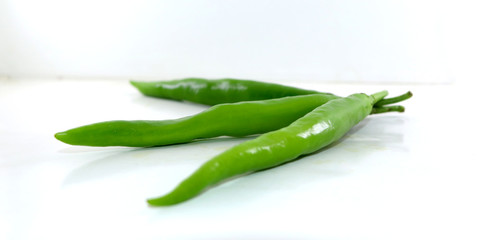 bunch of fresh green chili peppers on a white background