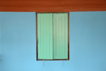 Obraz na płótnie Canvas green wood window on blue cement wall