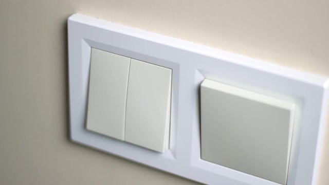 Close up of Caucasian hand, index finger, turns on and turns off light switch