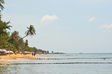 green palm trees and people on the public beach of Phu Quoc island Vietnam