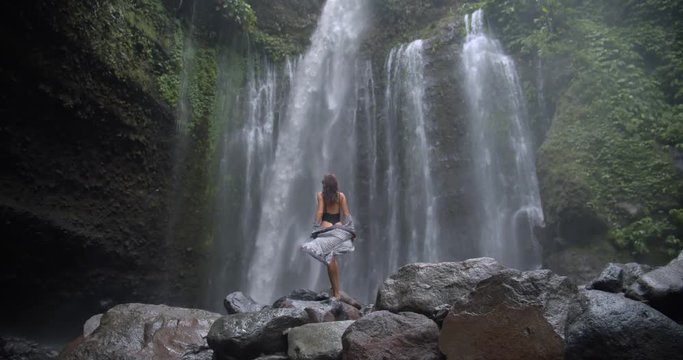 the waterfall in the middle of the jungle down from great height back view perfect model admires the wild nature