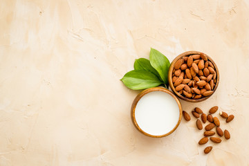 Almond milk near nuts on beige background top-down copy space