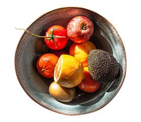 Fruit bowl with fresh tomatoes, lemons, avocado, kiwi fruit, apples. Isolated.