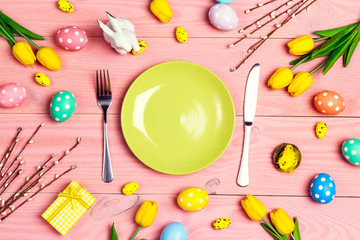 Table setting with cutlery and easter decorations on pink wooden table