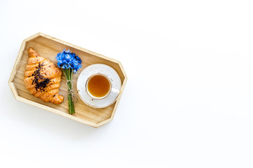 Breakfast with summer flowers. Tea, croissant and cornflowers on white background top-down copy space