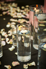 Aroma candle in glass, flower petals on floor