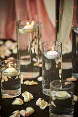 Aroma candle in glass, flower petals on floor