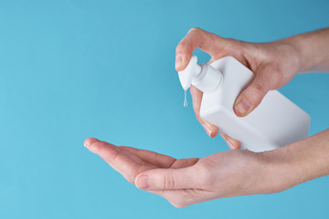 Concept of COVID-19 outbreak health protection with antiseptic. Woman wash hands using sanitizer or antiseptic gel as prevention measure for coronavirus on a blue background