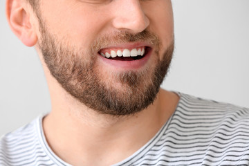 Smiling young man on light background, closeup