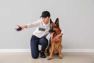 Female police officer with dog near light wall