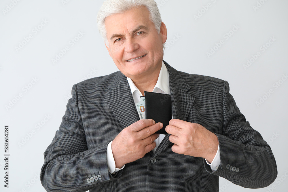 Poster Senior businessman with purse on light background