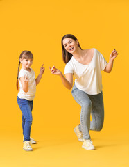 Fototapeta premium Happy mother and her little daughter dancing against color background