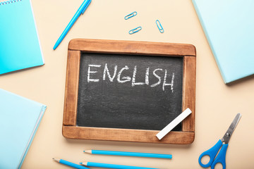 Chalkboard with text ENGLISH and stationery on color background