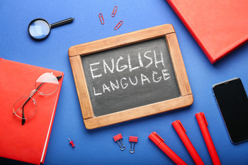 Chalkboard with text ENGLISH LANGUAGE and stationery on color background