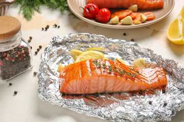 Foil with cooked salmon fillet on table