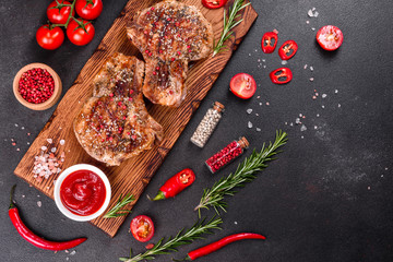 Fresh delicious juicy steak on the bones with vegetables and spices against a dark background